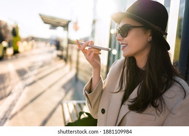 Girl talking on the phone on the speaker while sitting at the bus stop - Powered by Shutterstock