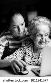 Girl Teaches Her Grandmother To Work On The Computer. Black And White Photo.