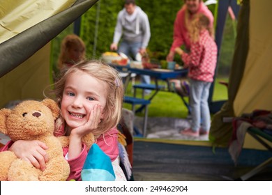 Girl With Teddy Bear Enjoying Camping Holiday On Campsite 