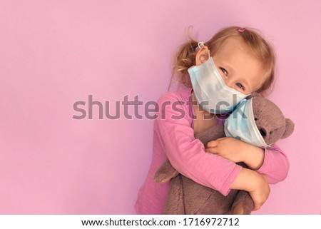 Girl with teddybear in face mask. Caucasian child wears facemask for protect during coronavirus Covid-19 epidemic.