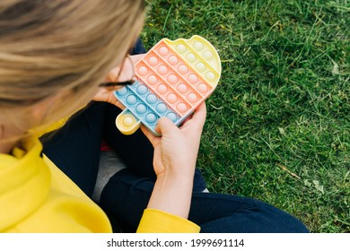 Girl Teen Playing Colorful Poppit Sensory Game. Close Up Of Kid Hands Pushing Multi Colorful Trendy Pop It Bubble Flexible Fidget Toy. Anxiety Relief, Antistress, Mental Health Concept.