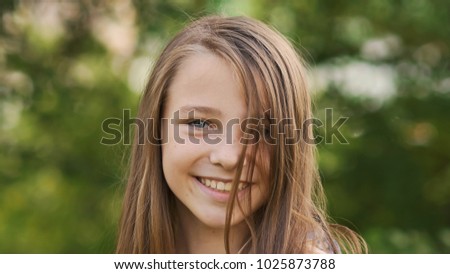 Girl teenager face close-up with freckles and funny posing embarrassed and playing with his hair.