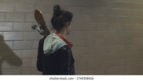 Girl teenager goes at night in the underpass. Young caucasian woman with skateboard in dark underground tunnel. Urban city lifestyle. - Powered by Shutterstock