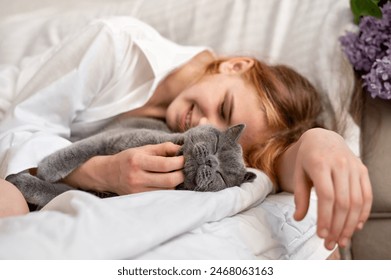 Girl teenager sleeping on bed together with cat, child and pet friendship and love, person take care about domestic animal. - Powered by Shutterstock