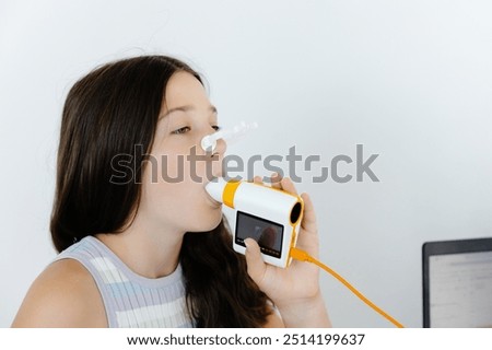 Girl testing breathing function by spirometry in doctors office. Diagnosis of respiratory function in pulmonary disease.