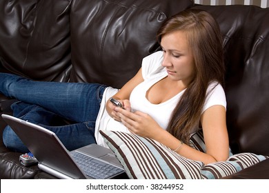Girl texting on the couch while watching TV and doing homework