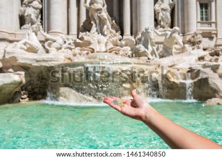 Girl is throwing coin at Trevi Fountain for good luck. A girl hand keeping coin. Trevi Fountain, Rome, Italy. 
