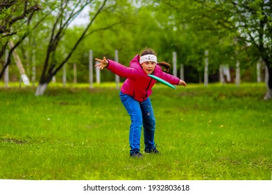 girl throws a disc on a green lawn