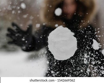 The girl throws a snowball at the camera. The snowball shatters into snowflakes.