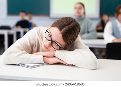 Girl is tired and sleeping at the desk in the classroom - Powered by Shutterstock