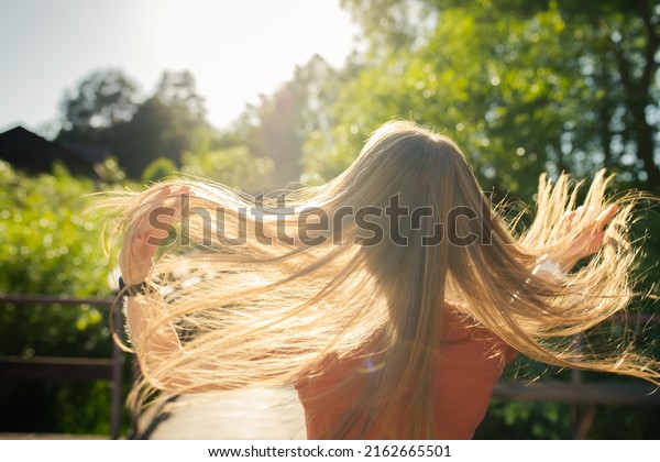 A girl tosses her long\
beautiful hair in the sun. The concept of hair care and healthy\
hair. Front view.