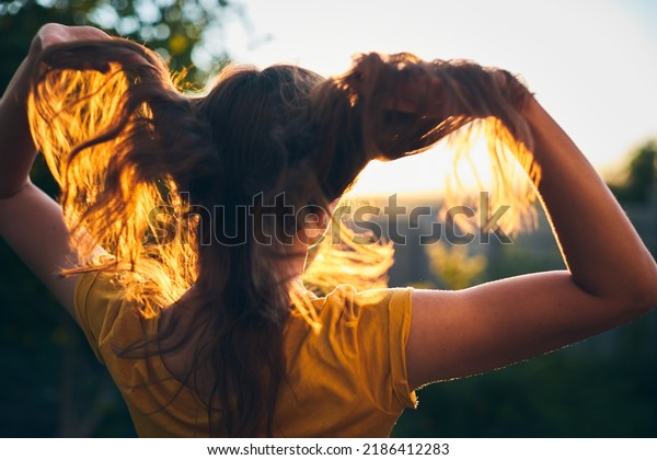 A girl tosses her long\
beautiful hair in the sun. The concept of hair care and healthy\
hair. Front view.