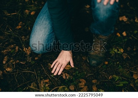 The girl touches the ground with her palm in the autumn forest. Forest bathing. Communication with the earth. Close-up