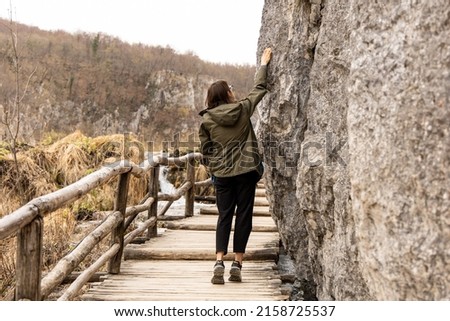 Girl is touching rocks in plitvice lakes, autumn