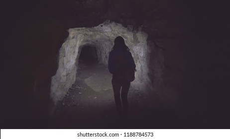 Girl Tourist Is A Cave With A Flashlight From Behind