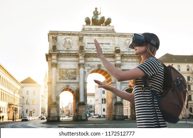 Girl tourist in glasses virtual reality. Virtual trip to Germany. The concept of virtual tourism. Sightseeing Triumphal arch in Munich in the background.