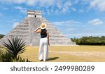 Girl tourist in a hat stands against the background of the pyramid of Kukulcan in the Mexican city of Chichen Itza - Mayan pyramids in Yucatan, Mexico
