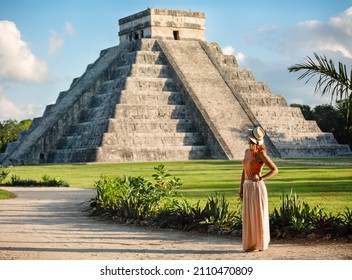 Girl tourist in a hat stands against the background of the pyramid of Kukulcan in the Mexican city of Chichen Itza. Travel concept.Mayan pyramids in Yucatan, Mexico