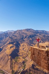 Girl Tourist On An Extreme Ledge In The Rock Troll Tongue. View Of The Caucasus Range, Dagestan.
