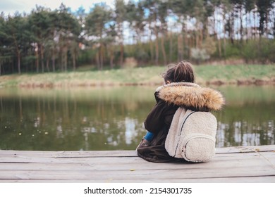Girl tourist sits on the bank of the river and enjoys the beautiful view