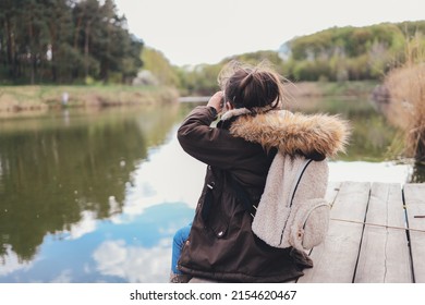Girl tourist sits on the bank of the river and enjoys the beautiful view