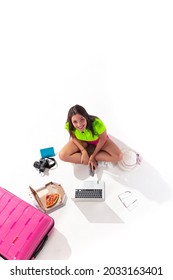 
Girl Tourist Sits On The Floor With A Laptop. Flat Lay Photo. Traveler Girl Isolated On A White Background. Travel Concept. The Girl At The Airport.