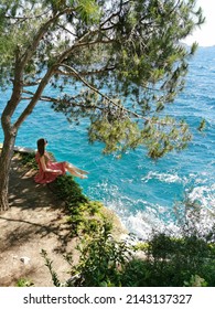 Girl tourist sits in a pine forest on the rocks on a background of beautiful seascape. Mediterranean Sea in Turkey, Kusadasi. Summer background