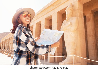 A Girl Tourist And Traveler With A Map Is Exploring The Sights Of The Ancient City Of Thebes Or Modern Luxor Standing Near The Temple Of Pharaoh's Queen Hatshepsut