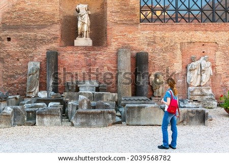 Girl tourist visits Baths of Diocletian in Rome, Italy. It is landmark of Rome. Young female person looks at Ancient Roman building in Rome city center. Concept of people, travel, past and history.