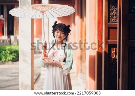 The girl in traditional Chinese dress is in the garden