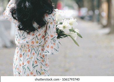The girl in traditional Vietnamese dress with lily flowers ( Hoa loa Ken ) in April every year in Hanoi, Vietnam