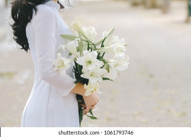 The girl in traditional Vietnamese dress with lily flowers ( Hoa loa Ken ) in April every year in Hanoi, Vietnam