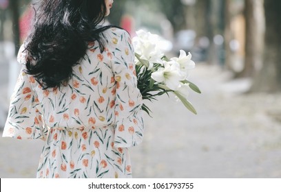 The girl in traditional Vietnamese dress with lily flowers ( Hoa loa Ken ) in April every year in Hanoi, Vietnam