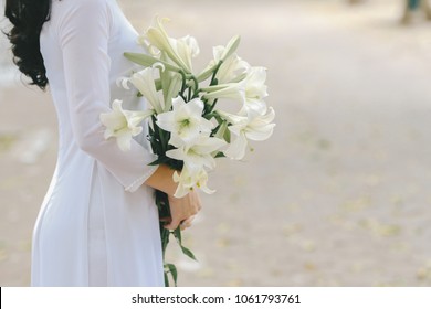 The girl in traditional Vietnamese dress with lily flowers ( Hoa loa Ken ) in April every year in Hanoi, Vietnam
