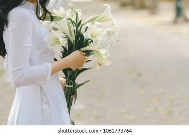 The girl in traditional Vietnamese dress with lily flowers ( Hoa loa Ken ) in April every year in Hanoi, Vietnam