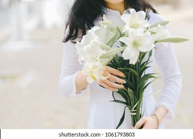 The girl in traditional Vietnamese dress with lily flowers ( Hoa loa Ken ) in April every year in Hanoi, Vietnam