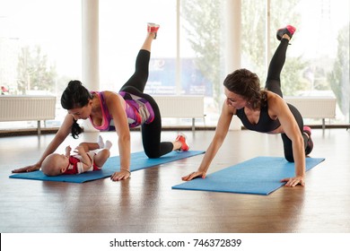 A girl with a trainer makes a swing with her foot while her baby lies on the rug - Powered by Shutterstock