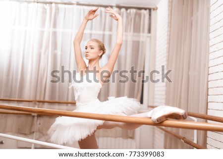 Girl is training stretching. She is dressed in a ballet tutu. She is the professional theater actor.