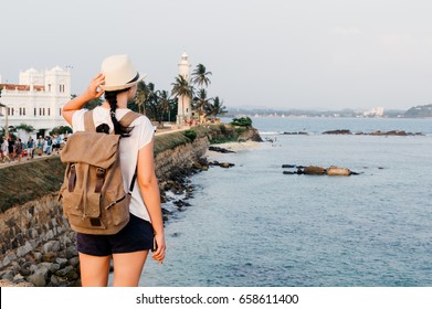 Girl traveler with a backpack. Light house at Galle Dutch Fort 17th centurys ruined dutch castle. That is unesco listed as a world heritage site in Sri Lanka.