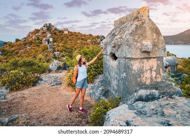 Girl traveler exploring ancient ruins of Lycian necroppolis city with fascinating Tombs and sarcophagus near Kekova island in Turkey. Historical sights and archeology