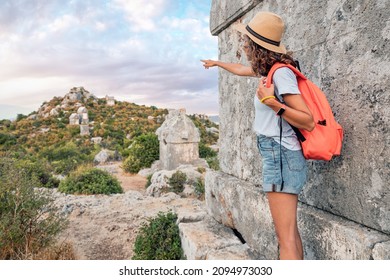 Girl traveler exploring ancient ruins of Lycian necroppolis city with fascinating Tombs and sarcophagus near Kekova island in Turkey. Historical sights and archeology