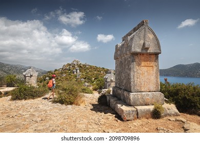 Girl traveler exploring ancient ruins of Lycian necropolis city with fascinating Tombs and sarcophagus near Kekova island in Turkey. Historical sights and archeology concept