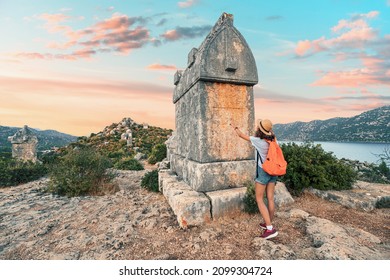 Girl traveler exploring ancient ruins of Lycian necropolis city with fascinating Tombs and sarcophagus near Kekova island in Turkey. Historical sights and archeology