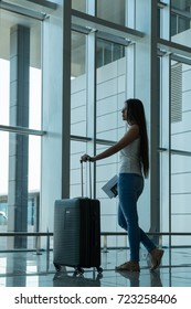 Girl traveler with a suitcase and documents to prepare for the next trip. The girl is standing at the airport. The concept of travel. - Shutterstock ID 723258406