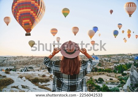 Girl traveler vacations beautiful destination in Goreme, Turkey. Fabulous Kapadokya with flying air balloons at sunrise, Anatolia