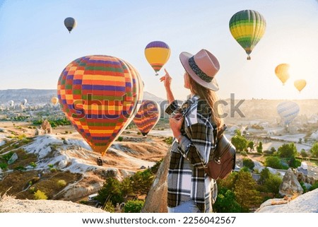 Girl traveler vacations in beautiful destination in Goreme, Turkey. Fabulous Kapadokya with flying air balloons at sunrise, Anatolia
