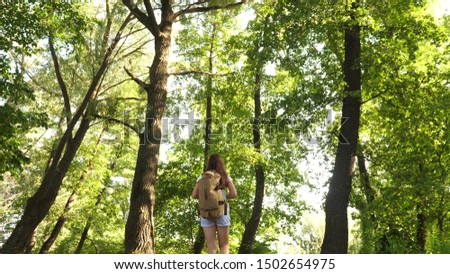 Girl traveler is walking through woods with a backpack. Hiker woman walks in the forest. happy hiker girl in summer park. teenager girl adventures on vacation.