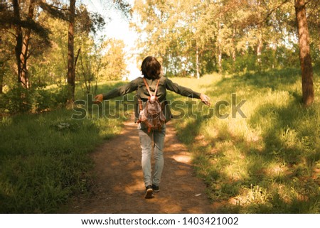Girl traveler in the wild, a girl with a backpack in the woods, a traveler walks along a forest path, a woman with a bag on her shoulders travels through a wild forest