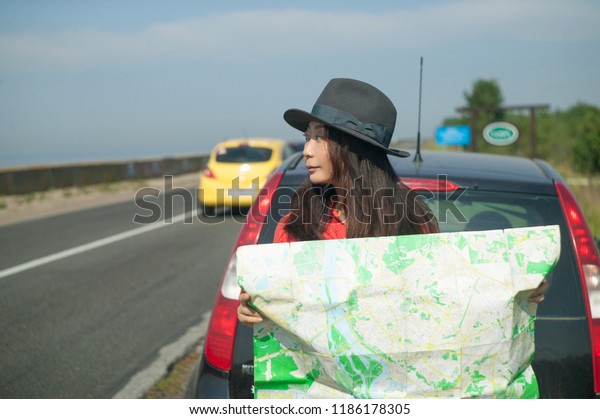 a girl is\
travelling by car with a map 