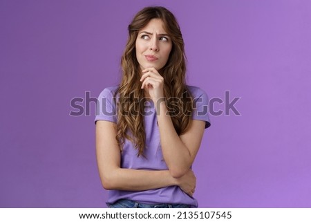 Girl trying solve problem thinking solution make hmm face smirk frowning thoughtful look away touch chin pondering making choice deciding how act what do stand purple background focused